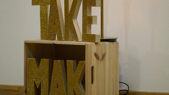 eine Holzkonstruktion mit der Aufschrift „TAKE MAK"